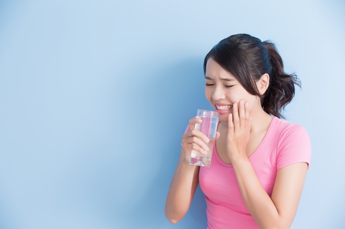 敏感な歯を持つ水を飲む女性